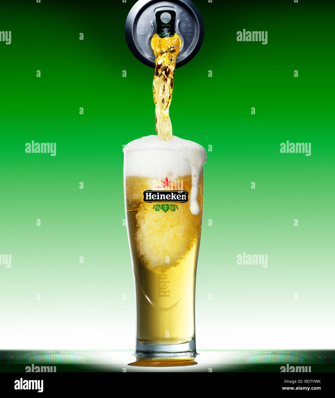 Can of Heineken pouring into overflowing pint glass Stock Photo