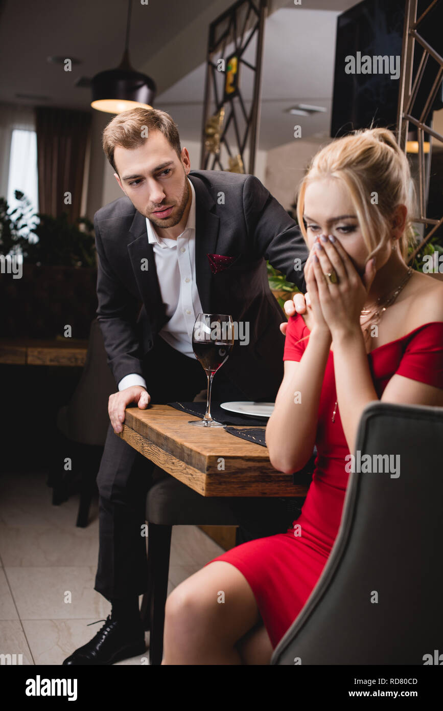 selective focus of blonde woman crying near worried boyfriend in