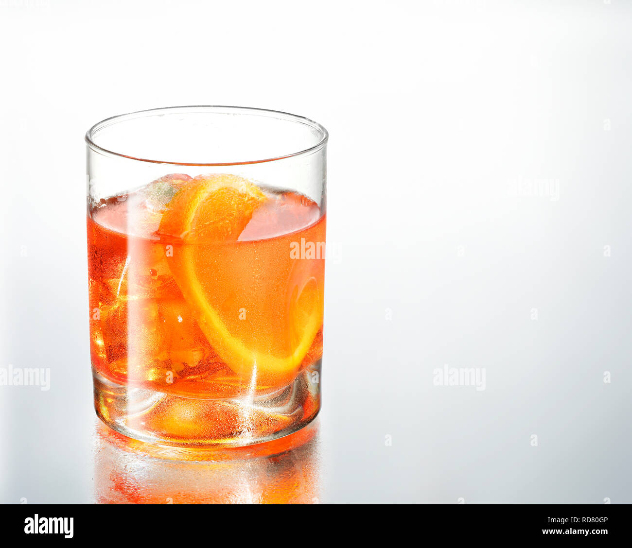 Glass of drink with a slice of orange, studio shot Stock Photo