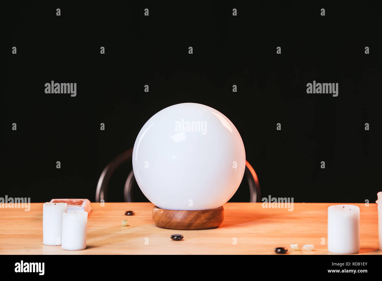 selective focus of crystal ball near candles on wooden table isolated on black Stock Photo