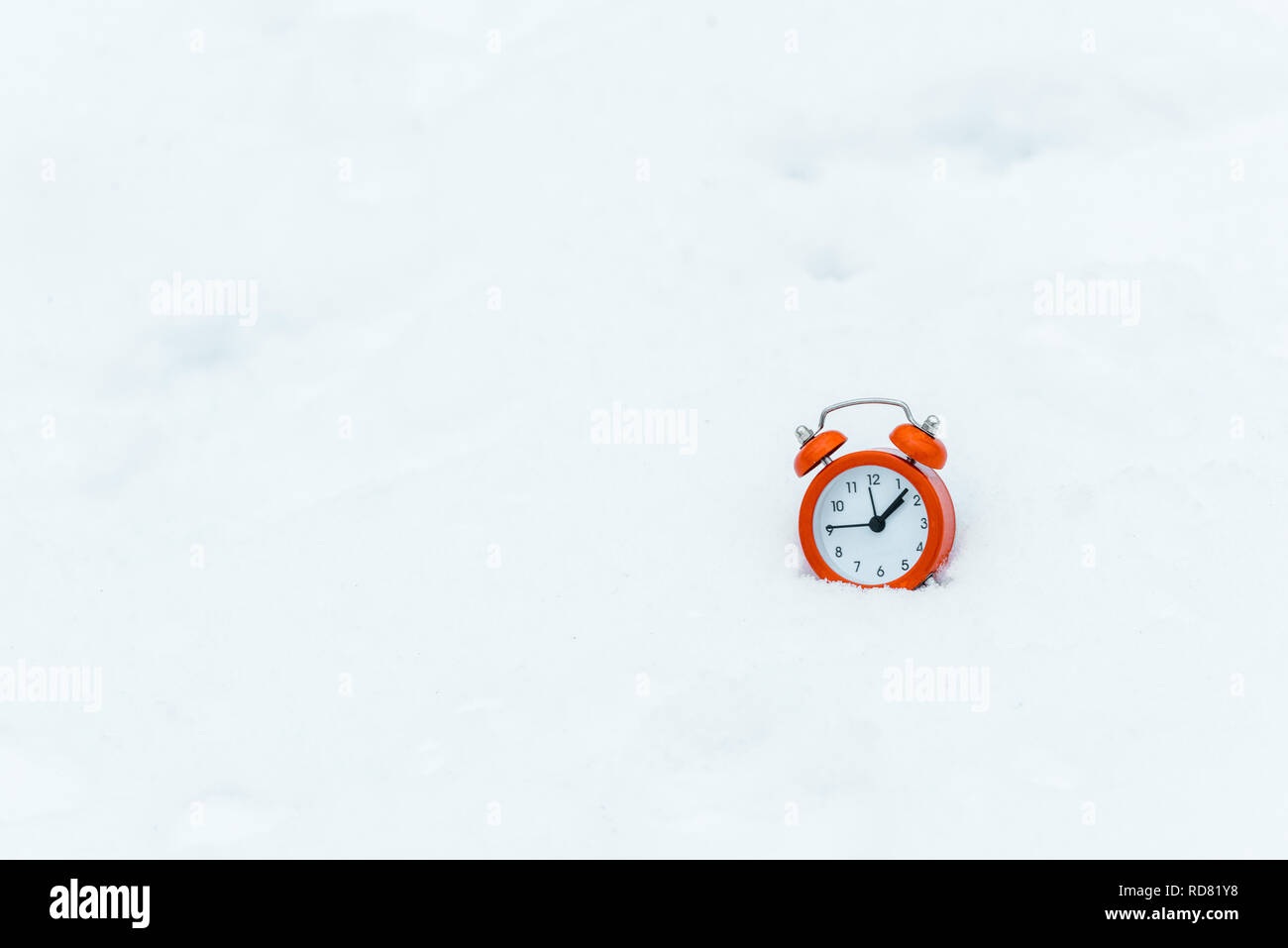 isolated in white of alarm clock standing on white snow Stock Photo