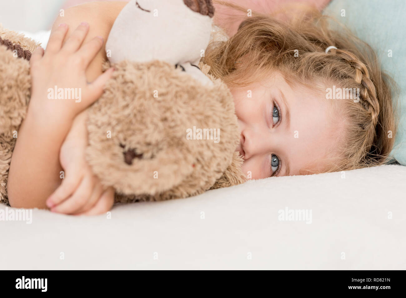 cheerful adorable kid hugging teddy bear on bed in children room Stock ...