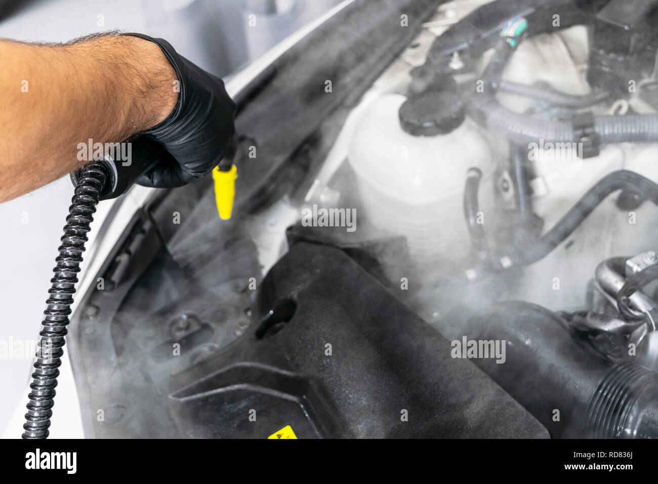 Car detailing. Car washing cleaning engine. Cleaning car engine using hot steam. Hot steam engine washing. Soft lighting. Car wash station worker clea Stock Photo