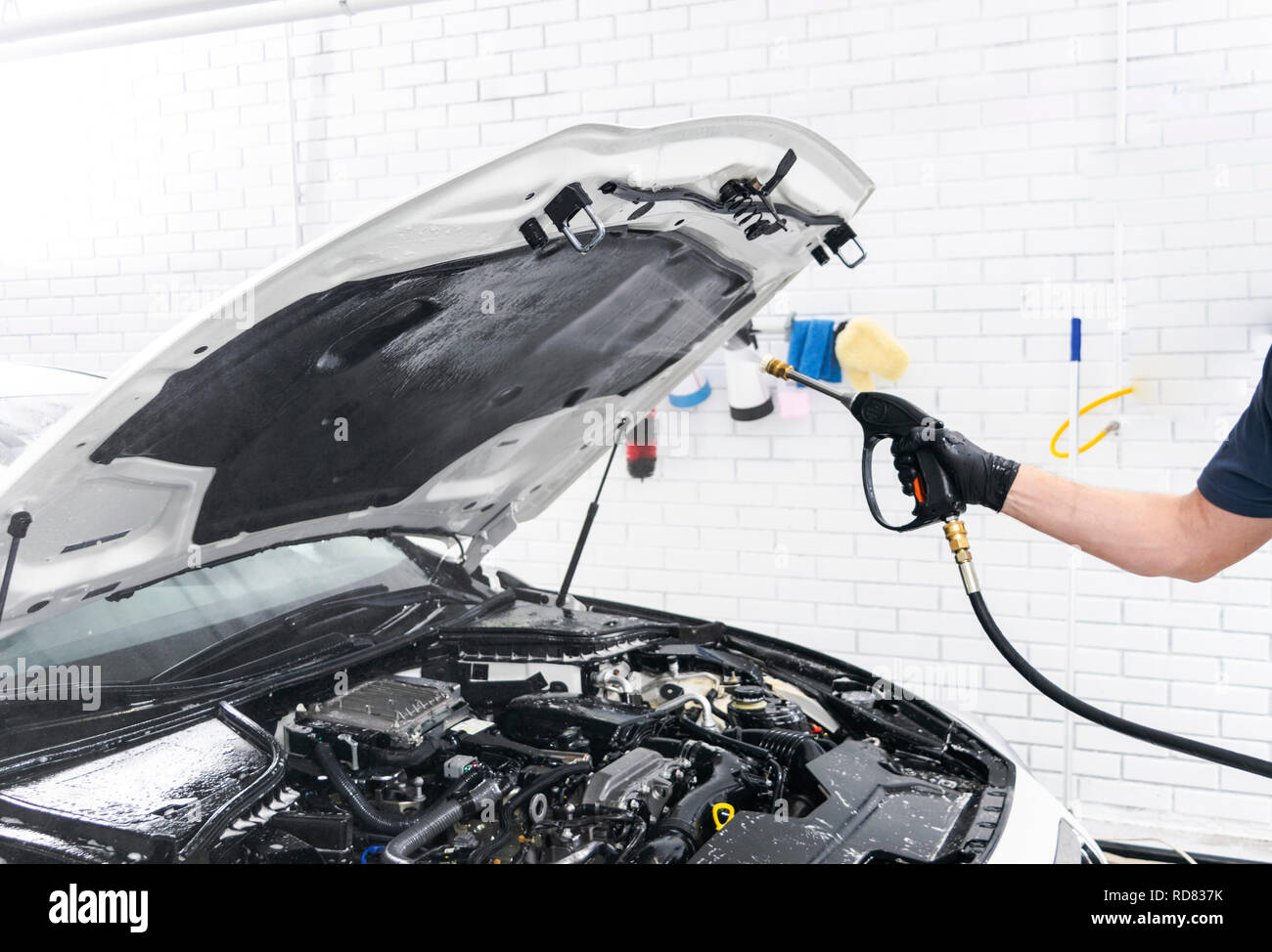 Car detailing. Manual car wash engine with pressure water. Washing car engine with water nozzle. Car washman worker cleaning vehicle engine. Man spray Stock Photo