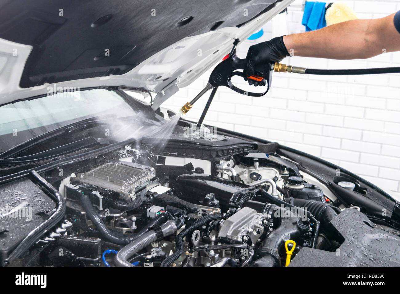 Car detailing. Manual car wash engine with pressure water. Washing car engine with water nozzle. Car washman worker cleaning vehicle engine. Man spray Stock Photo
