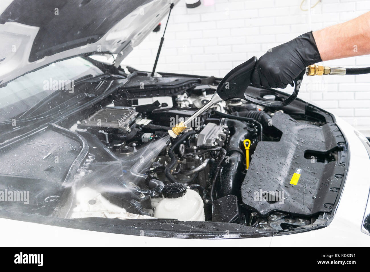 Car detailing. Manual car wash engine with pressure water. Washing car engine with water nozzle