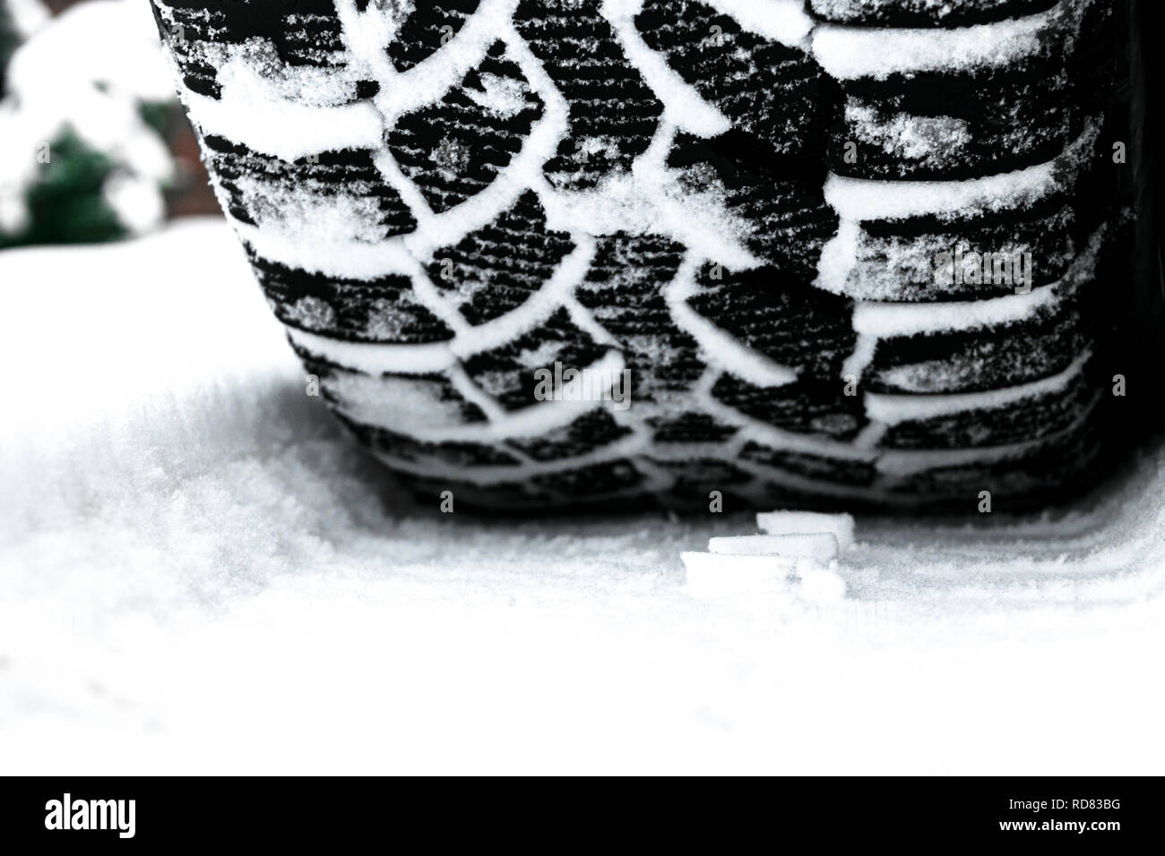 The car tire in the snow close up. Car tracks on the snow. Traces of the car in the snow. Winter tires. Tyres covered with snow at winter road. Stock Photo