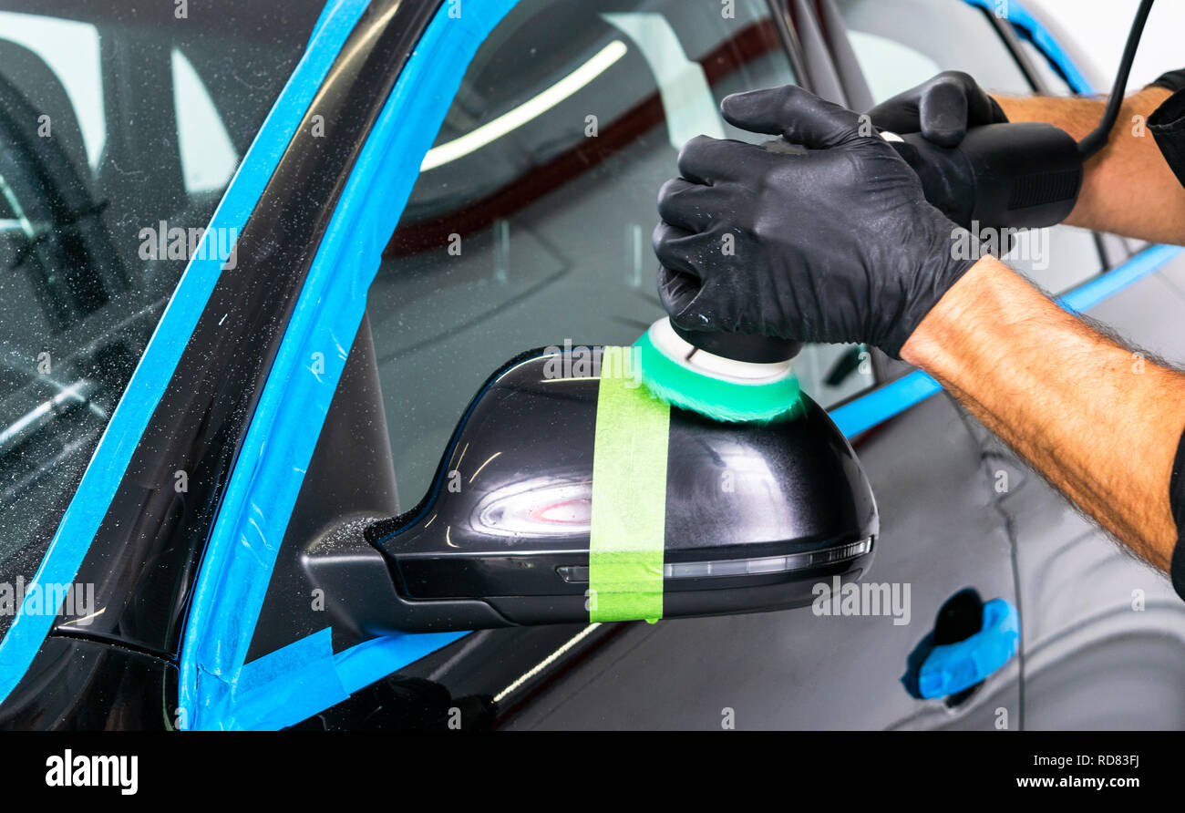 Car polish wax worker hands applying protective tape before