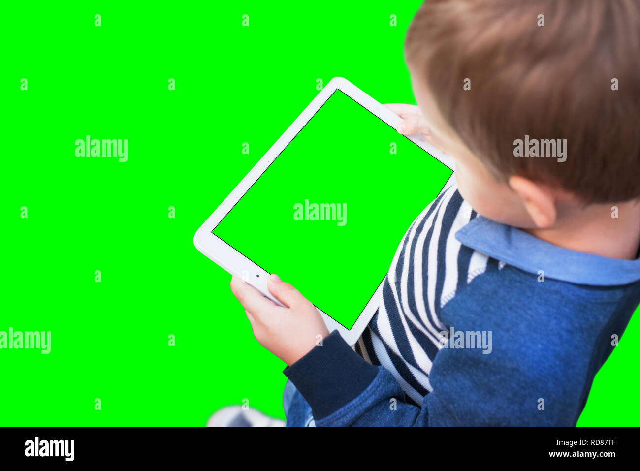 Boy play game on white tablet. Isolated screen and background in green, chroma key. Stock Photo