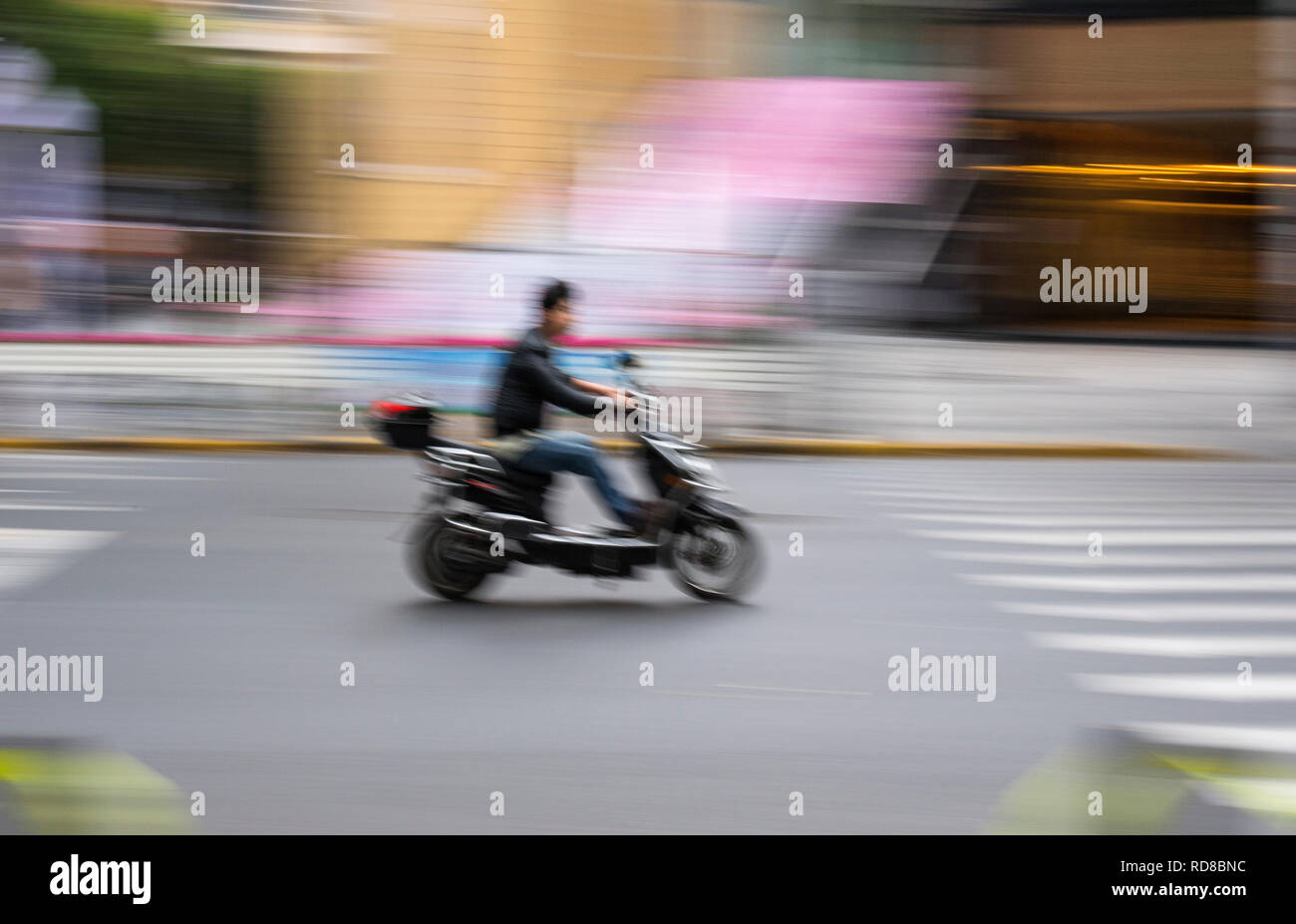 Man riding a scooter in Shanghai, China Stock Photo