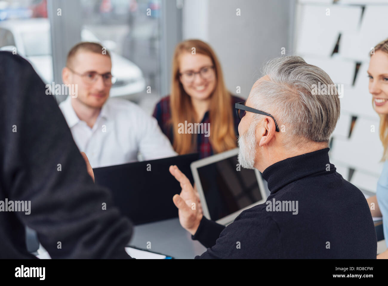 Senior team leading talking to his business team gesturing with his hands as he explains with focus to a young man and woman Stock Photo