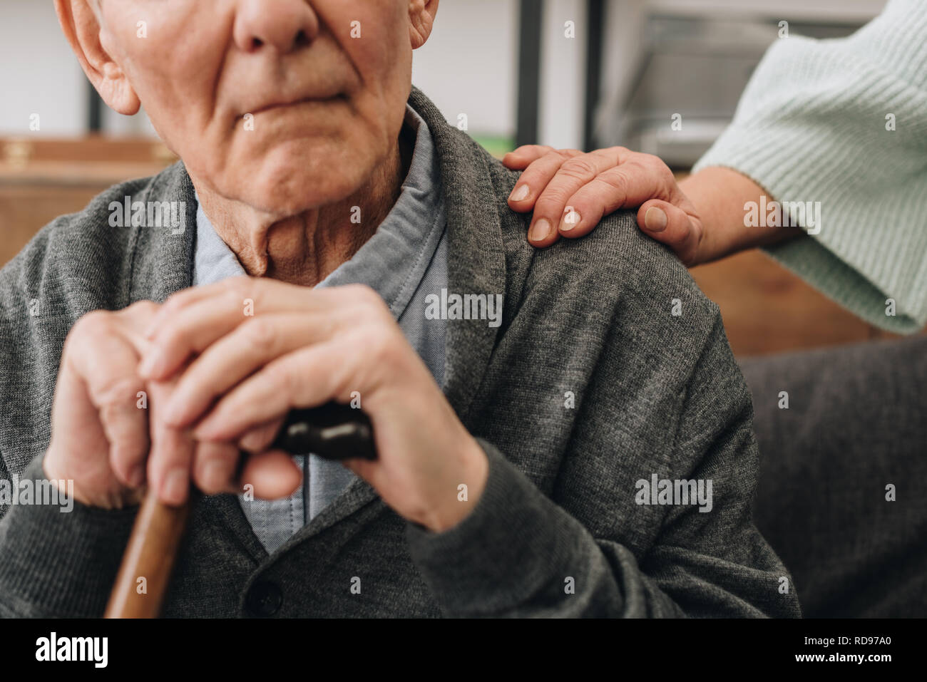 cropped view of retired husband sitting in living room and near senior wife Stock Photo