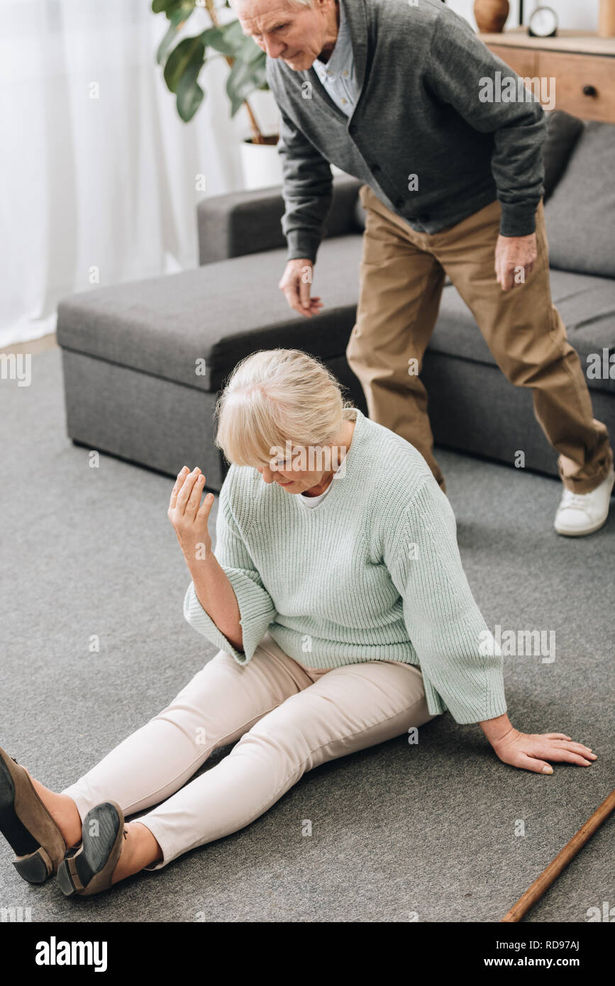 retired husband coming to upset wife sitting on floor Stock Photo