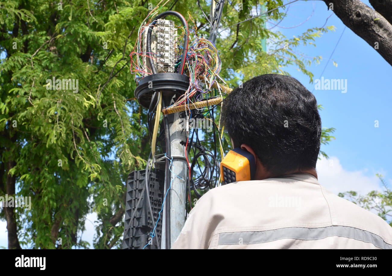 technician is plugging in a network cable to the line socket. Stock Photo