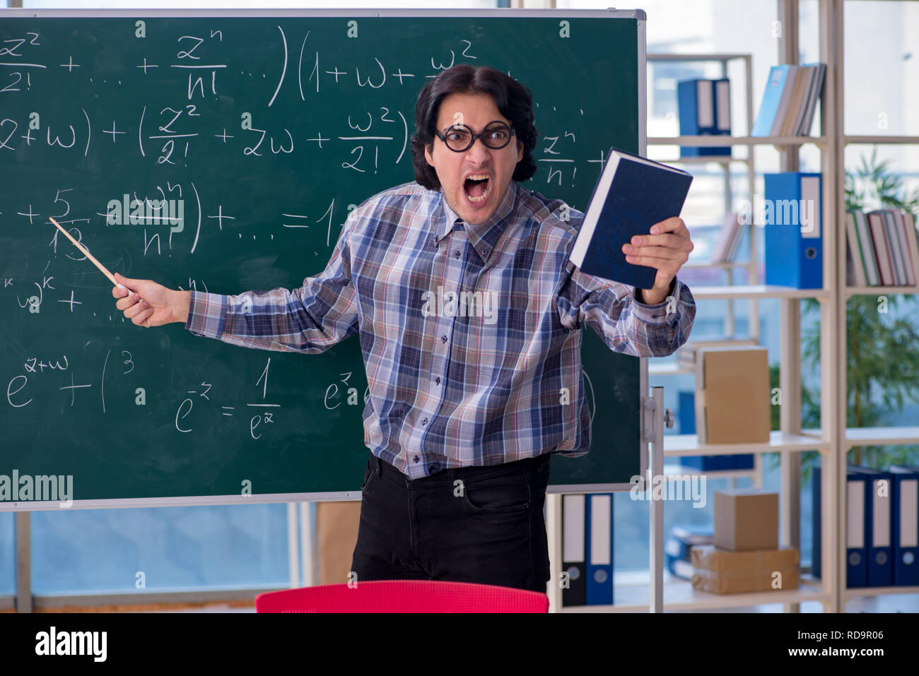 Grumpy Math Teacher Young funny math teacher in front of chalkboard Stock Photo - Alamy