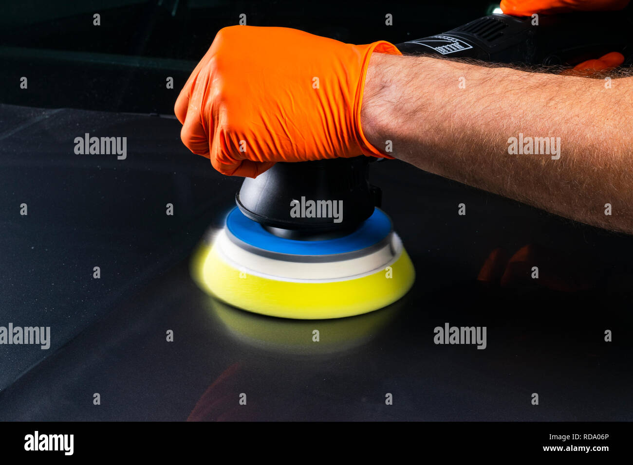 Car polish wax worker hands applying protective tape before polishing