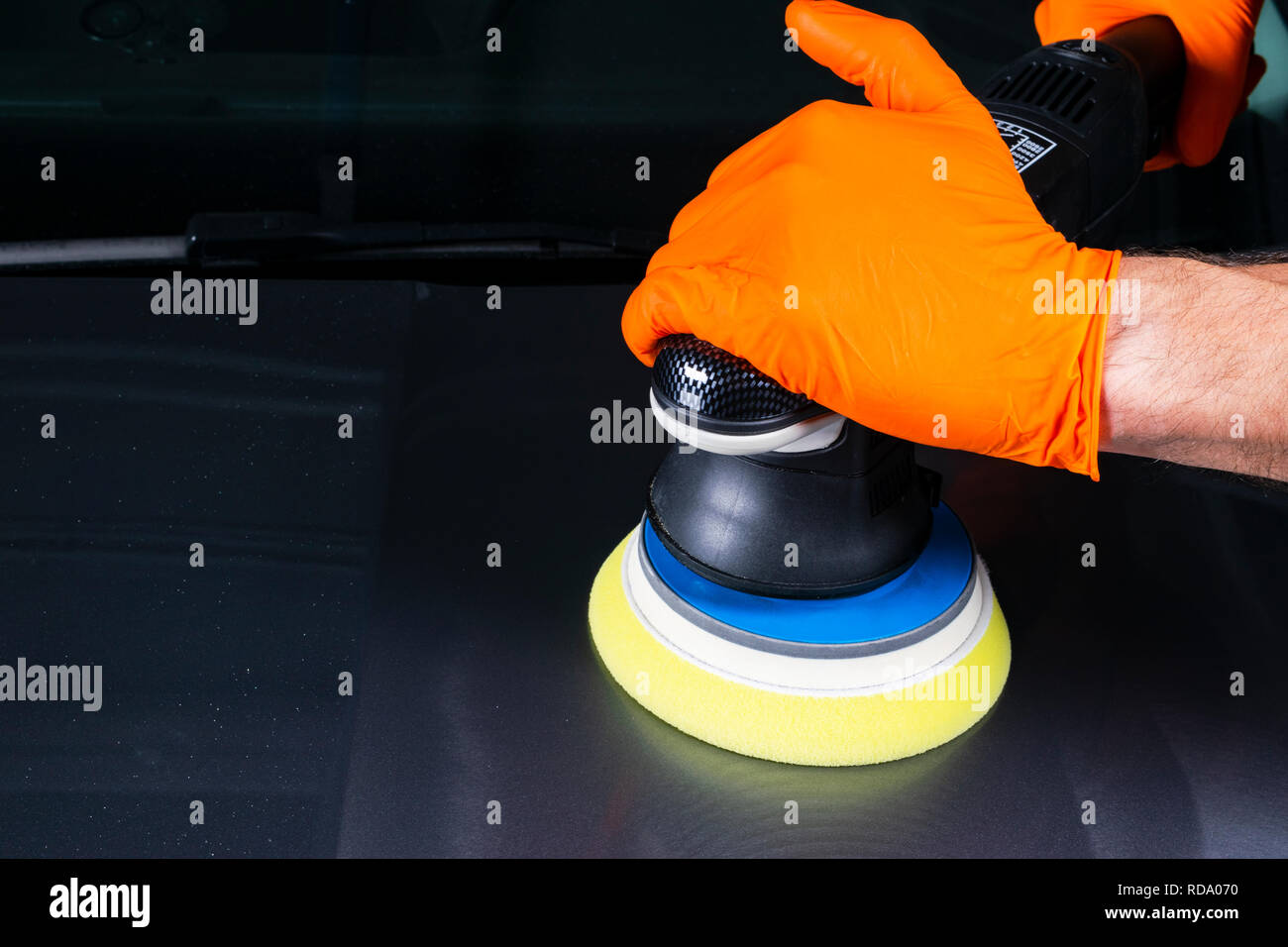 Car polish wax worker hands applying protective tape before polishing