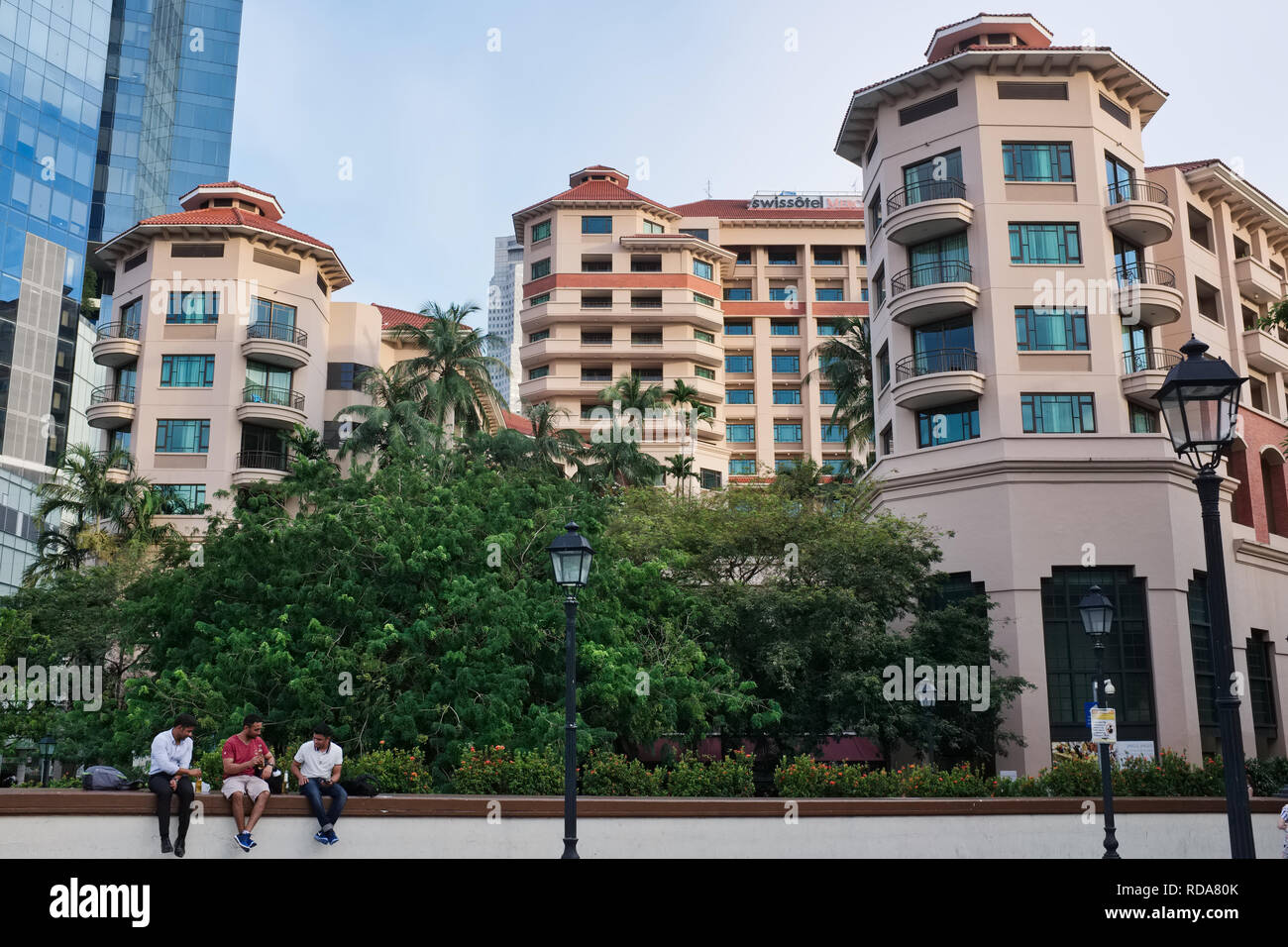 Three men drinking beer in front of Merchant Court Swissôtel, by the Singapore River, at Clarke Quay, Singapore Stock Photo