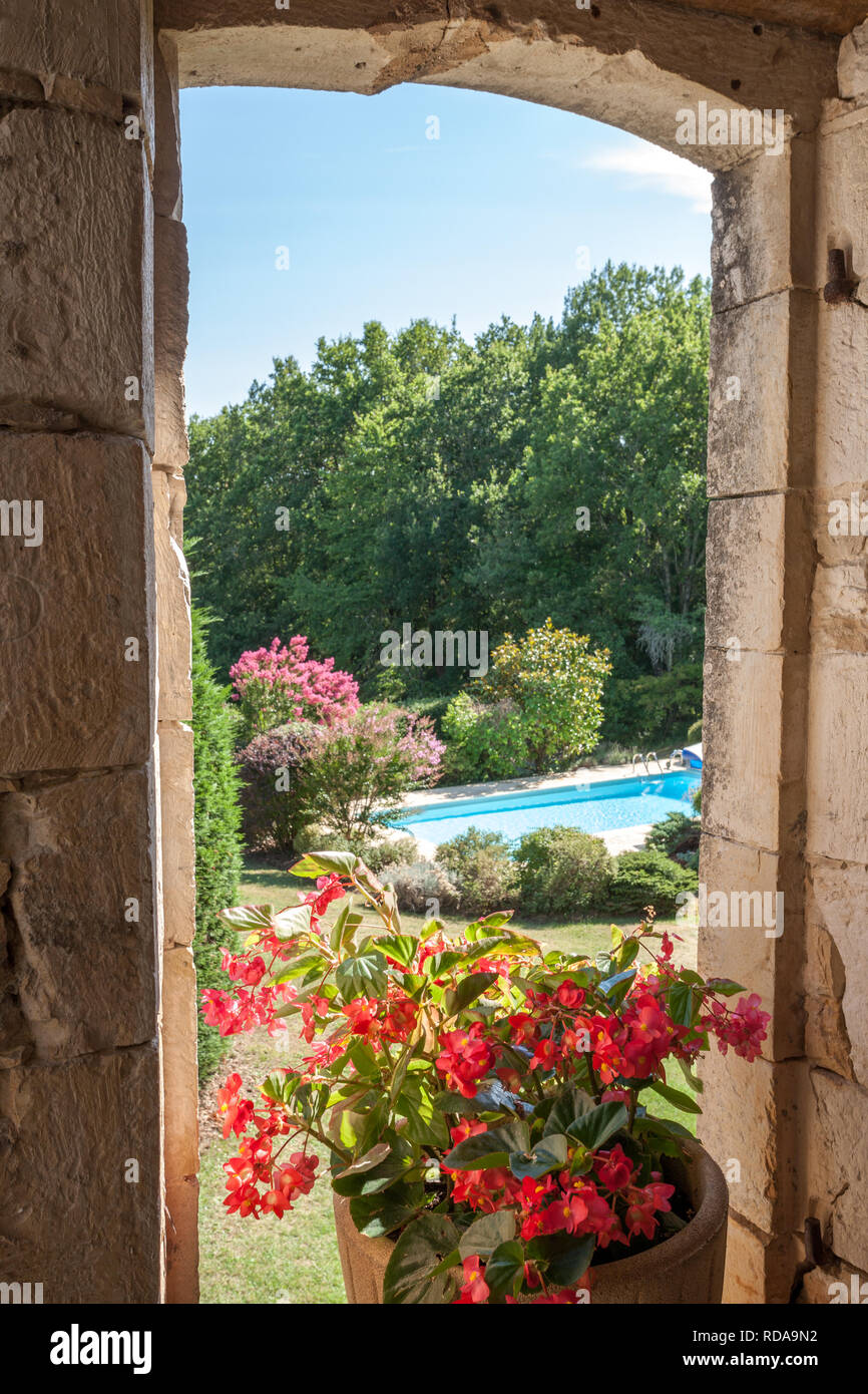 View of a swimming pool in the sunshine through an ols stone arched window Stock Photo