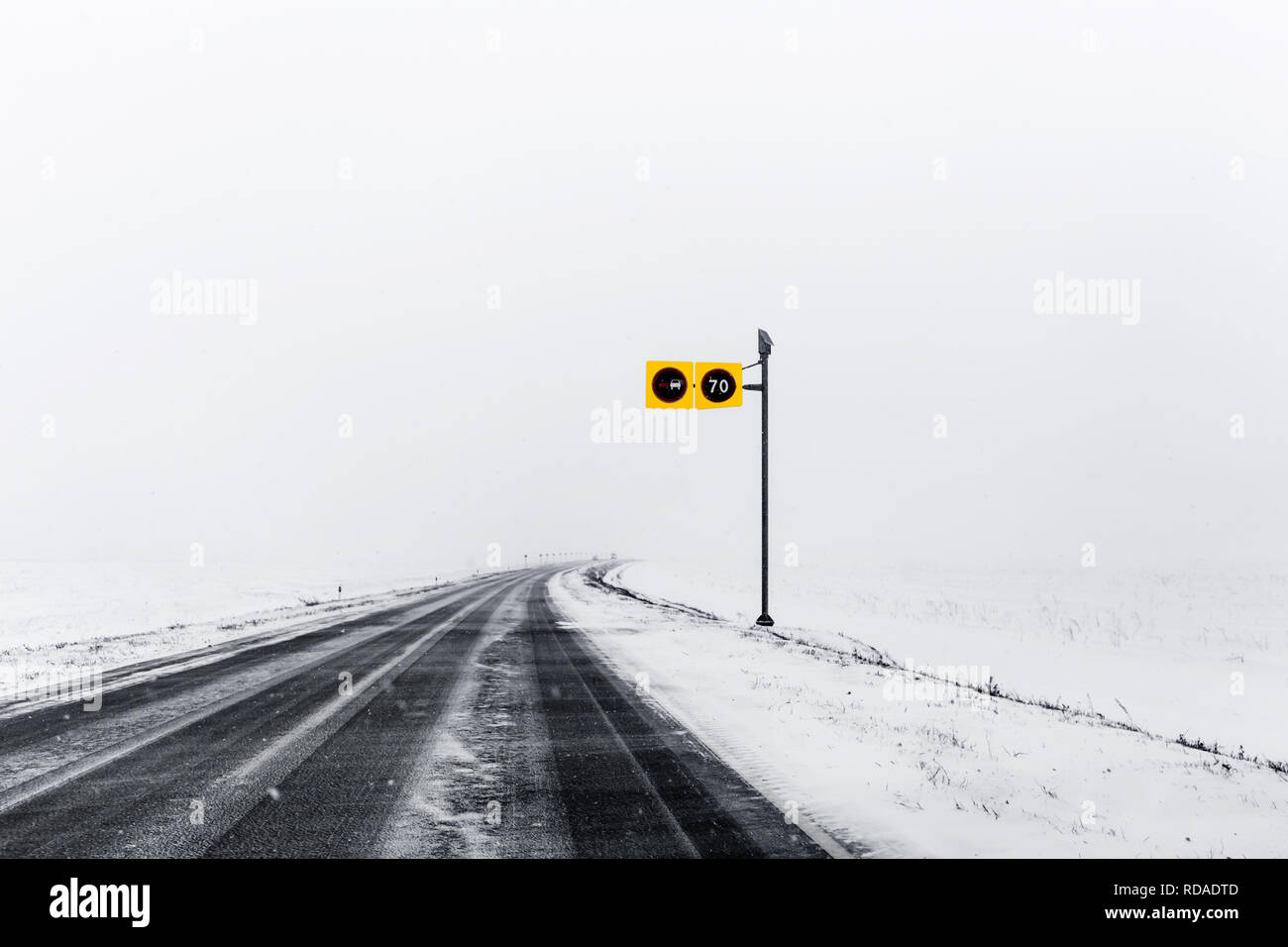 Asphalt road going through a snowy field Stock Photo - Alamy