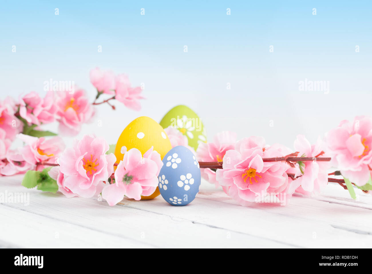 Colored eggs with pink flowers on white wooden background Stock Photo ...