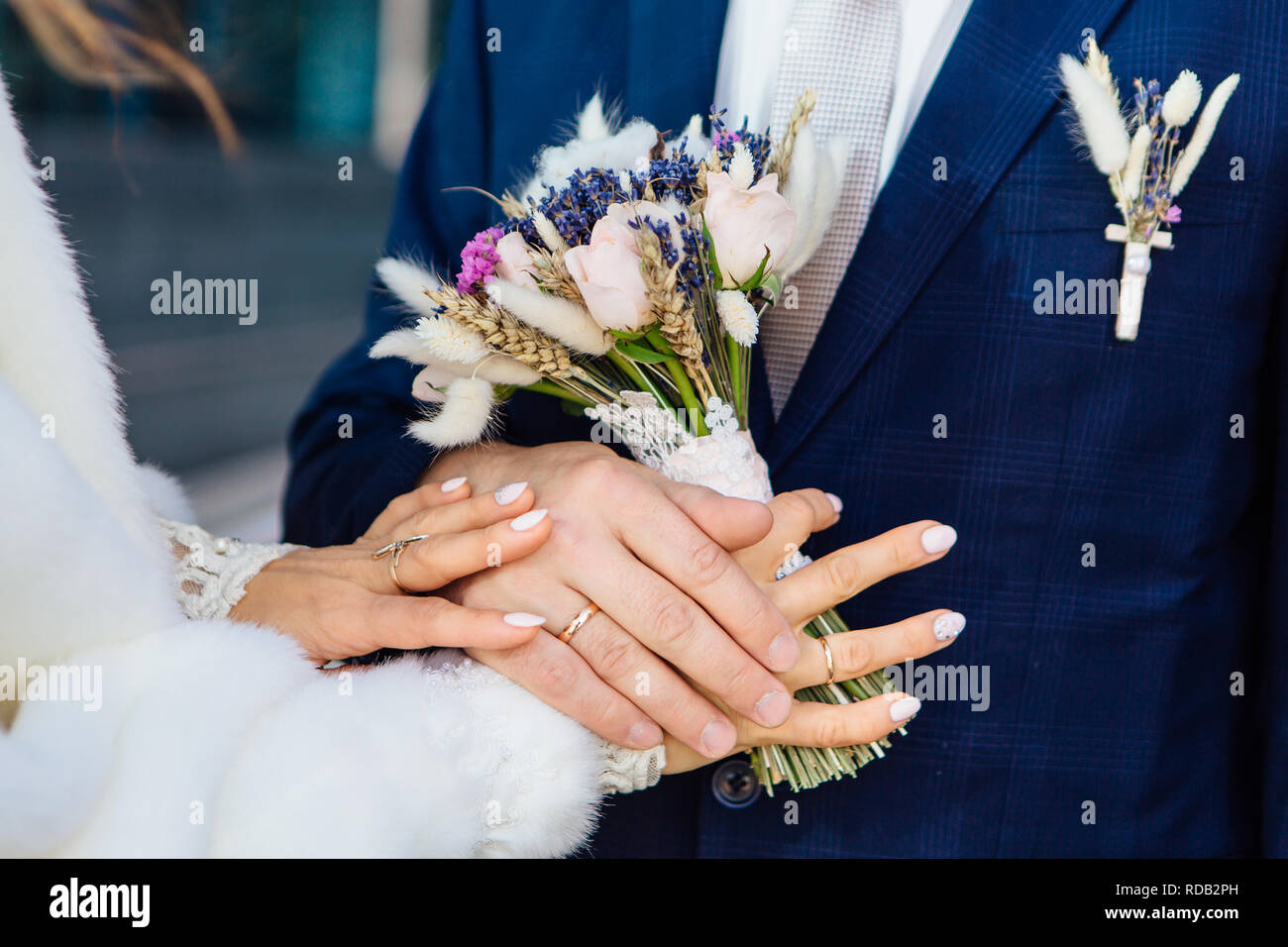 Hands of the bride and groom on the wedding bouquet Stock Photo - Alamy