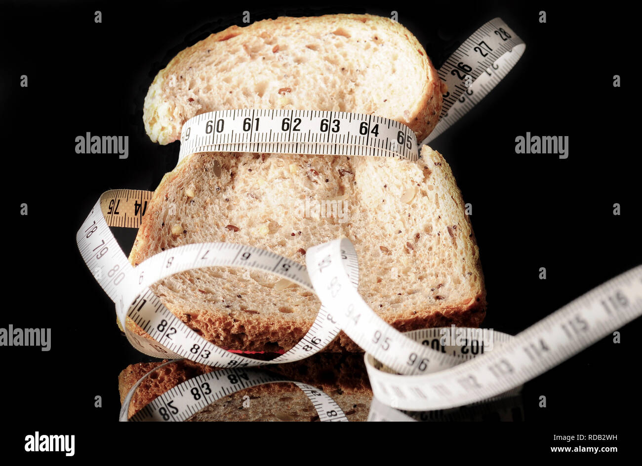 A slice of bread surrounded by a measurement tape on black with reflection Stock Photo