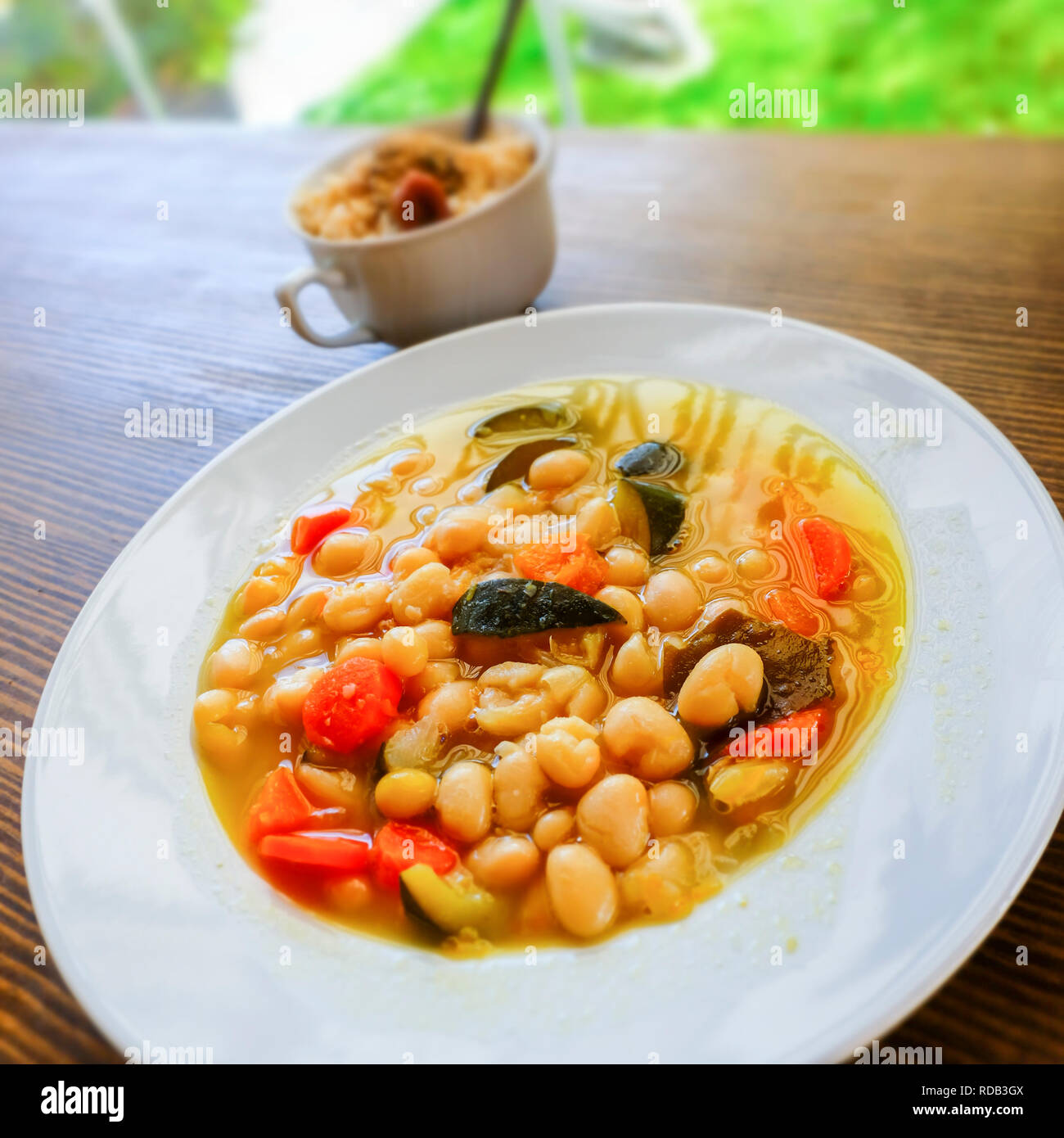 Pochas (Spanish string bean) with vegetables and kombu kelp (edible alga) and a cup of  brown rice with umeboshi (japanese pickled ume fruits). Macrob Stock Photo