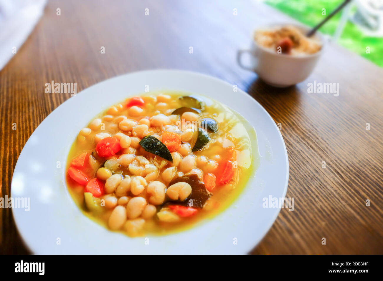 Pochas (Spanish string bean) with vegetables and kombu kelp (edible alga) and a cup of  brown rice with umeboshi (japanese pickled ume fruits). Macrob Stock Photo