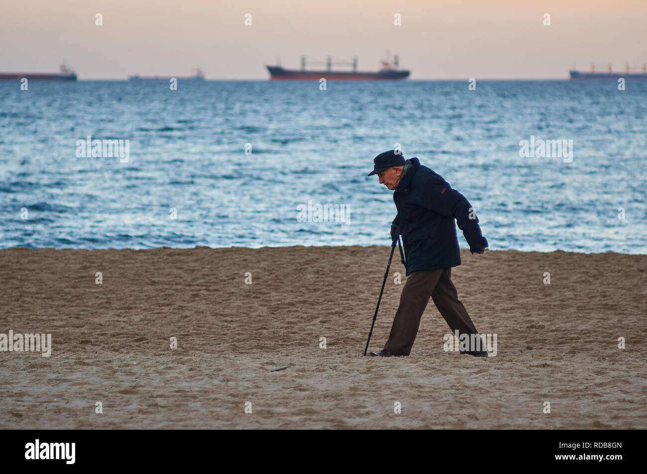 Gdansk, Poland: 26th December 2018 - An old man strolling along a Baltic sea beach with a walking stick, in winter. Stock Photo