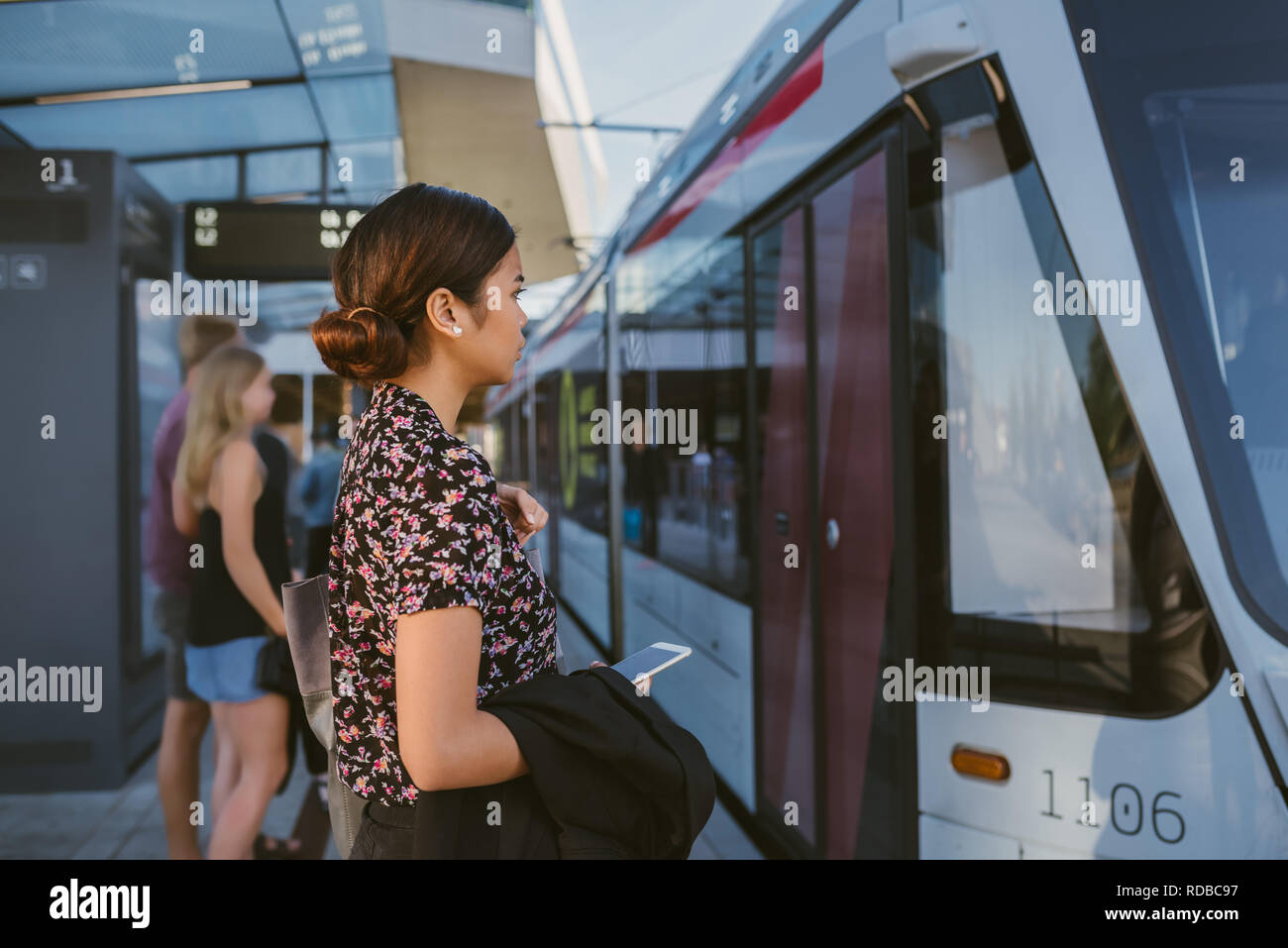 Young Asian businesswoman boarding a train during her work commute Stock Photo