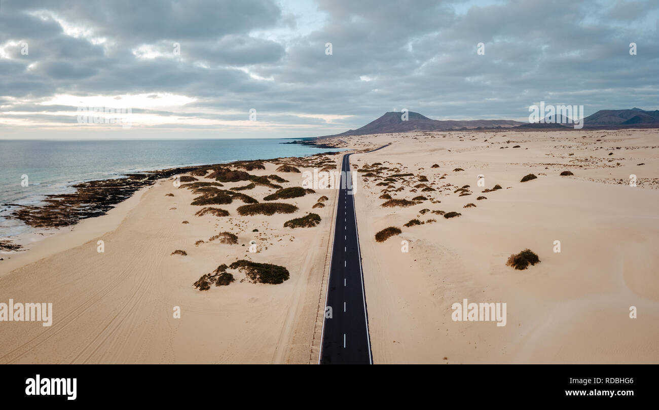 Aerial view of an empty road through the dunes at the sunrise with copy space Stock Photo