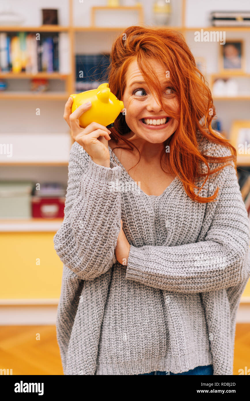Young woman shaking her piggy bank with glee as she imagines all the things she can do and buy with her savings Stock Photo