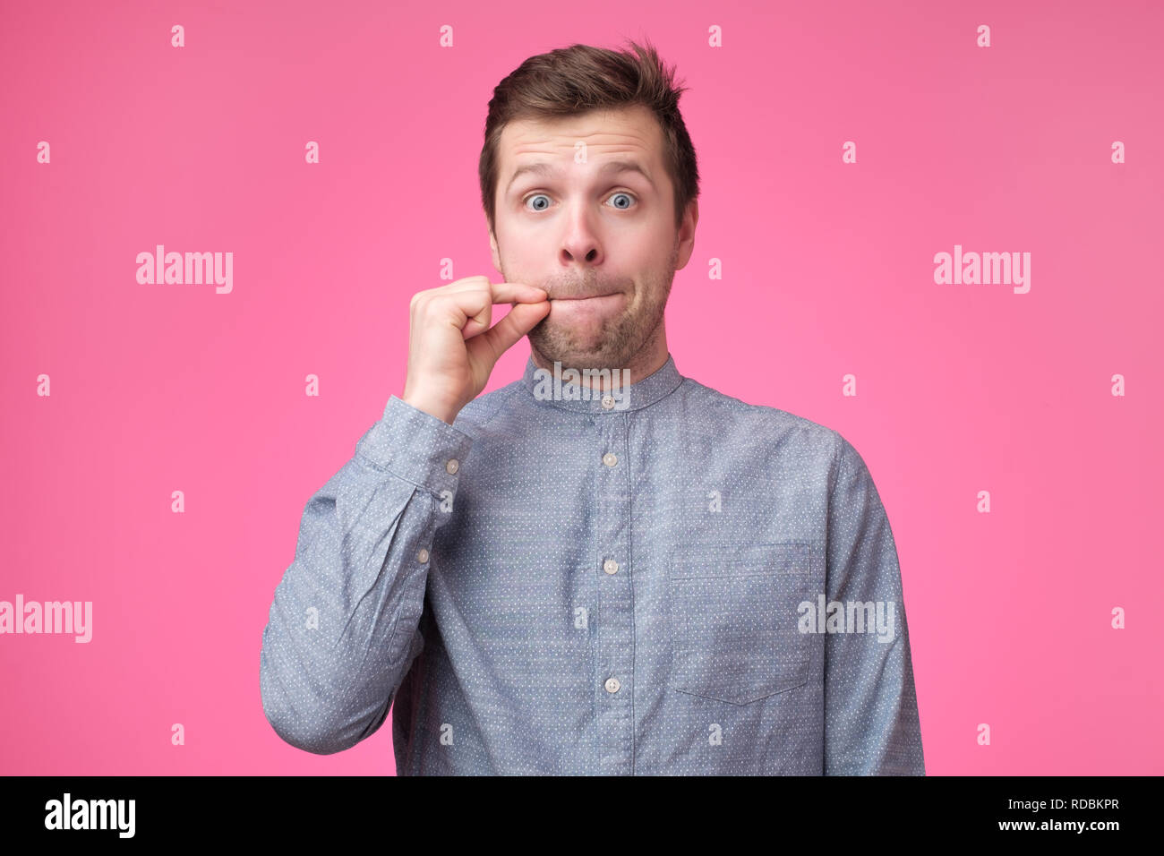 Young man showing a sign of closing mouth and silence gestur Stock Photo
