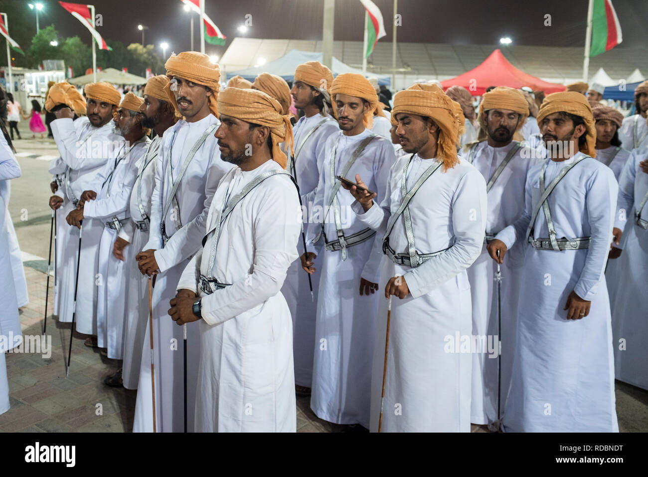 Men wearing Omani dress white dishdash and turban as they prepare to perform a traditional