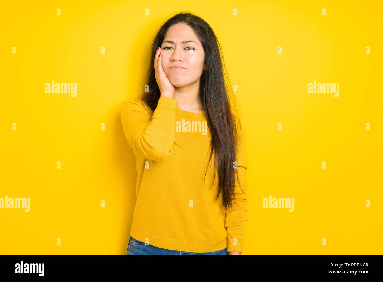 Beautiful brunette woman over yellow isolated background thinking ...
