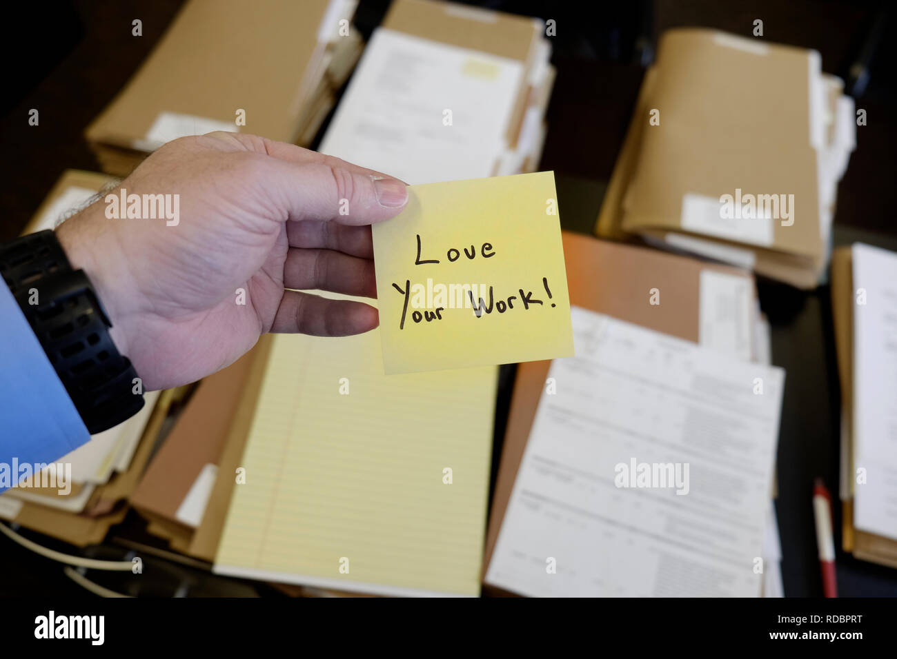 Sticky Note in Hand Businessman Desk Files Folder Working Message Motivation Love Your Work Stock Photo
