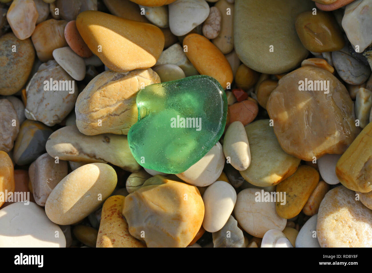 green weather worn glass on the beach with pebbles in Italy on the Adriatic coast in winter Stock Photo
