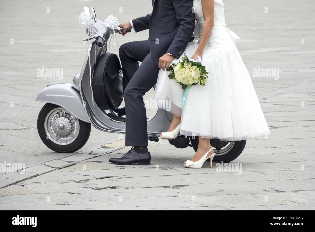 Young newlywed just married, posing on an old gray scooter Stock Photo