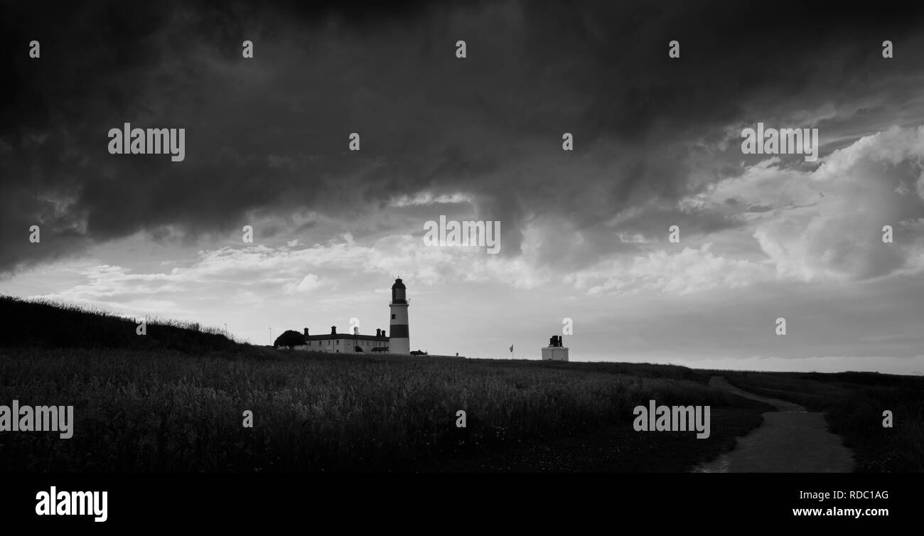 The heavy storm clouds roll over the North East coast threatening rain and blocking out the sunlight, throwing the lighthouse into silhouette. Stock Photo