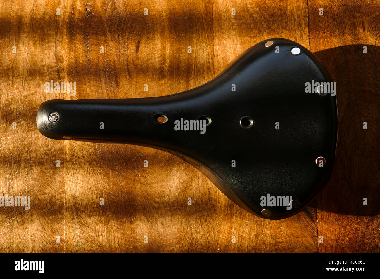 Brooks B17 standard black leather bicycle saddle on wooden table, top view Stock Photo