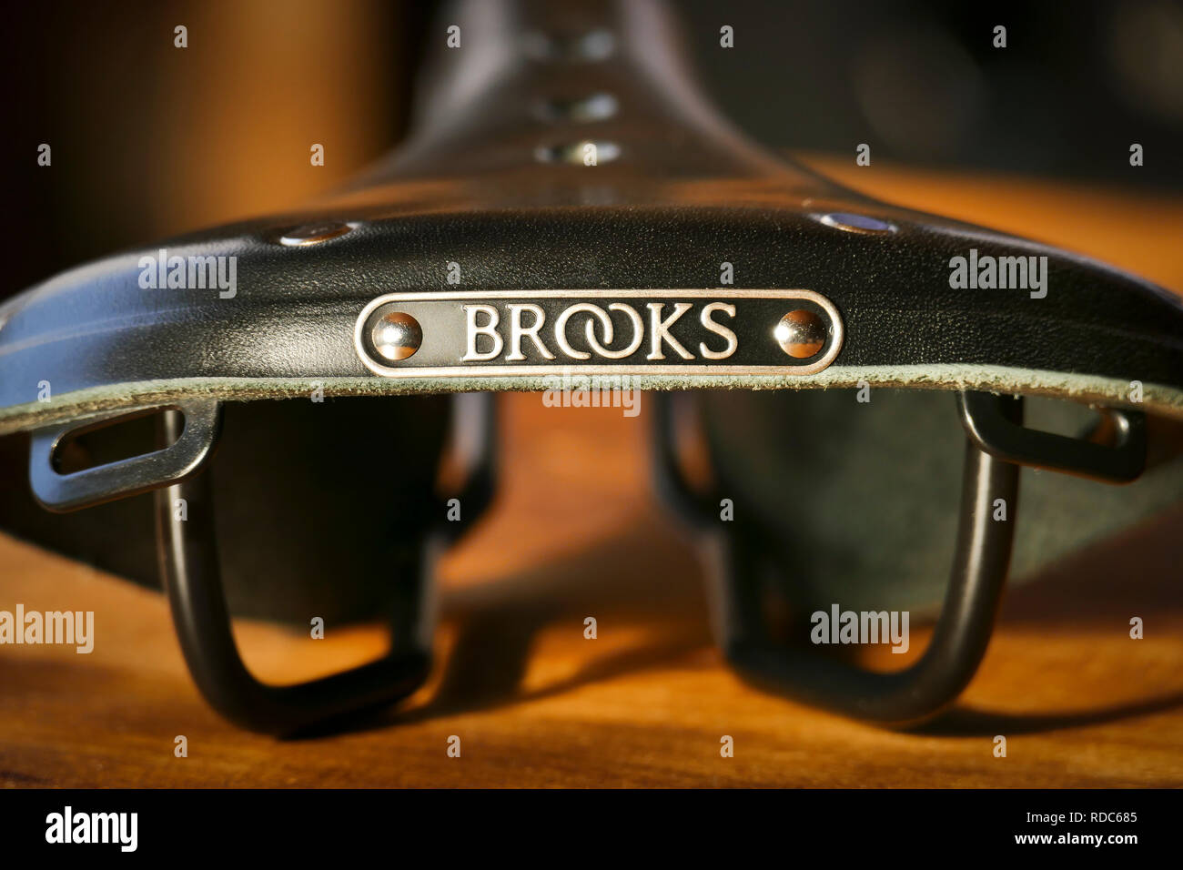 Brooks B17 standard black leather bicycle saddle on wooden table, rear view Stock Photo
