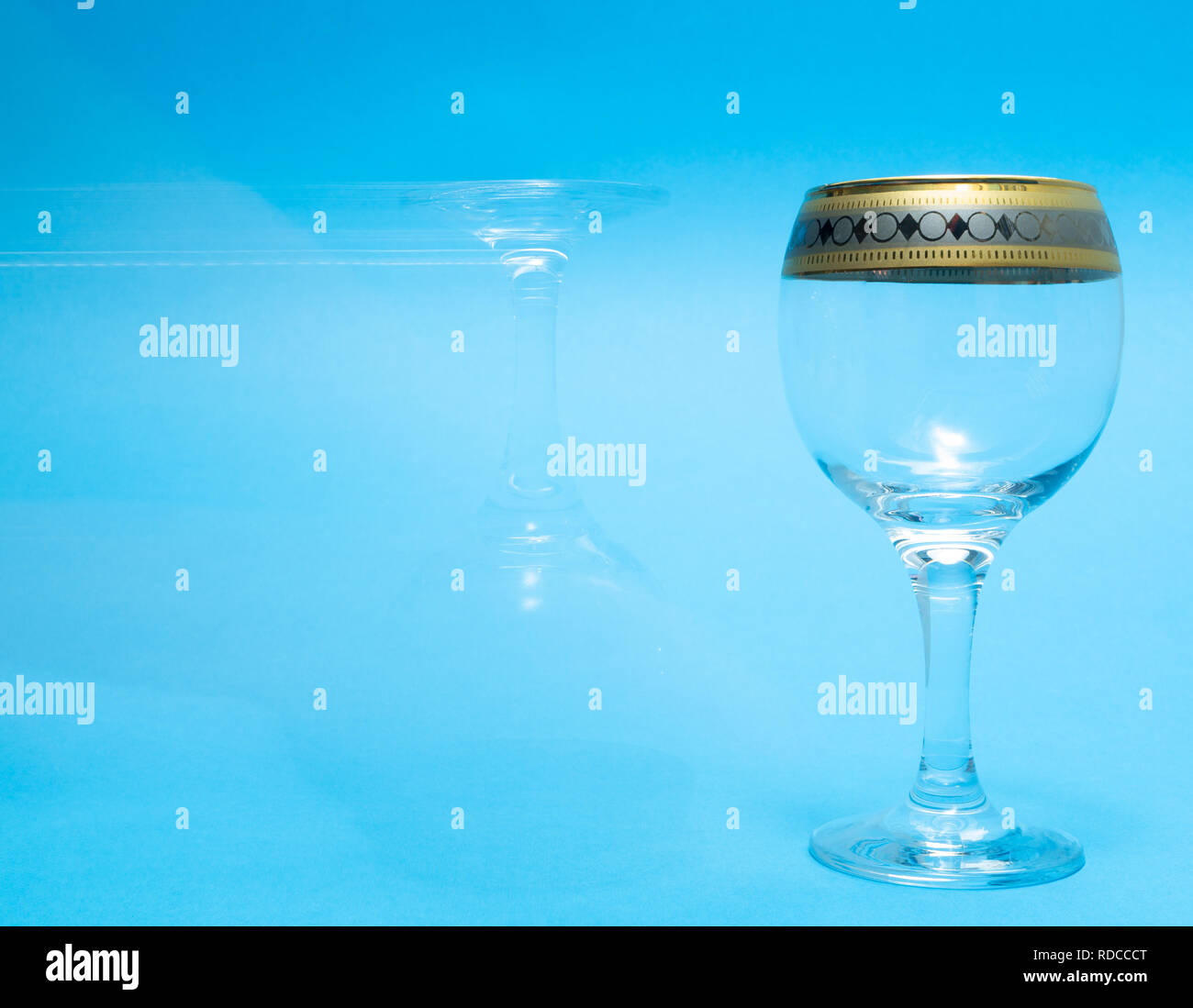 one empty and one ghost wine glasses on blue background Stock Photo
