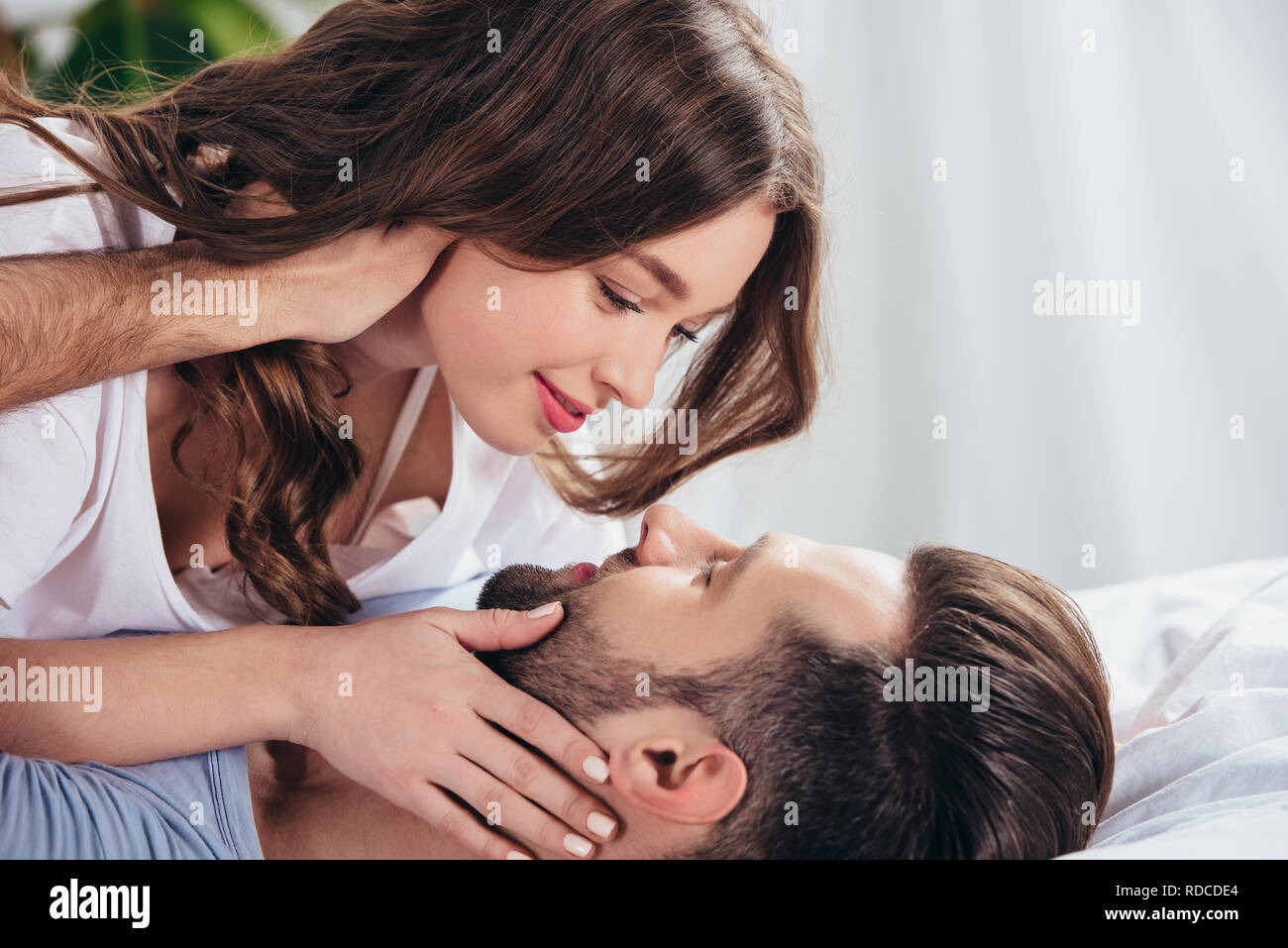 selective focus of young loving couple gentle looking into eyes and embracing in bed Stock Photo
