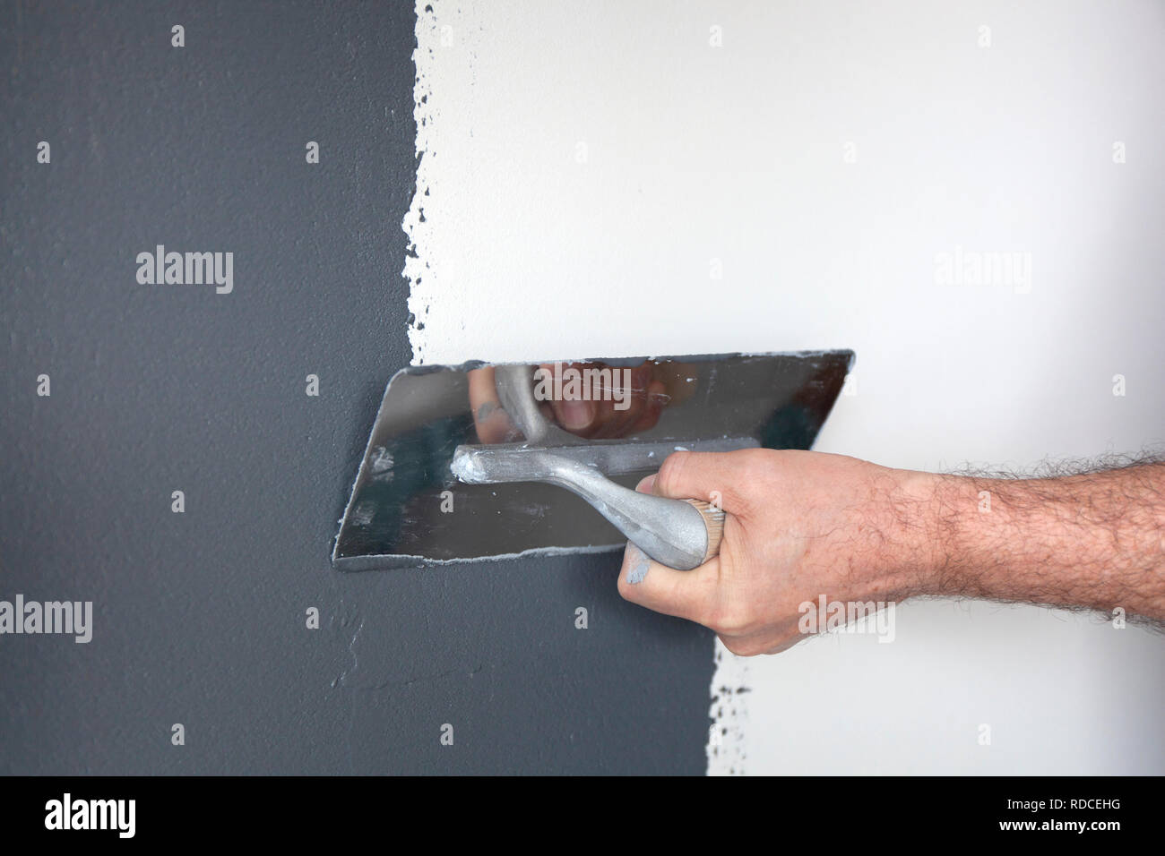 Hand with a trowel plastering a wall with decorative plaster Stock
