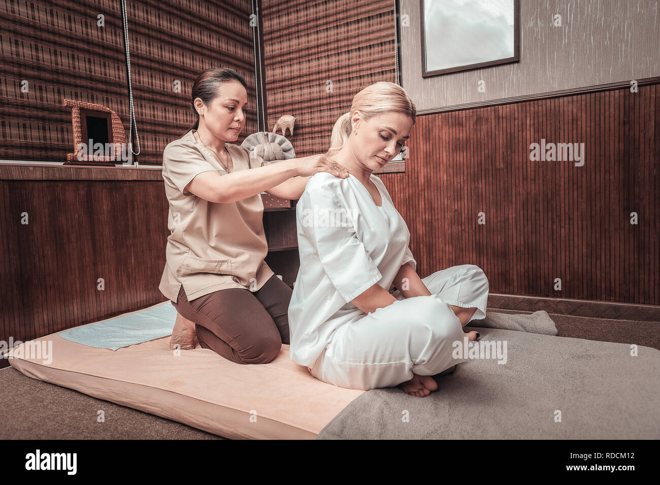 Professional female masseuse massaging her clients shoulders Stock Photo