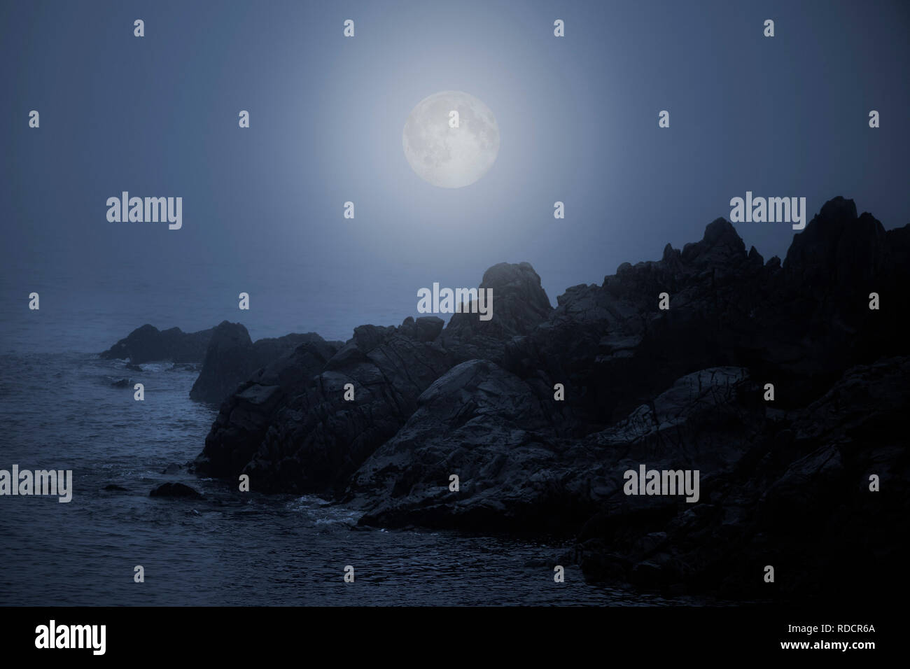 Rocky sea coast in a foggy full moon night Stock Photo - Alamy