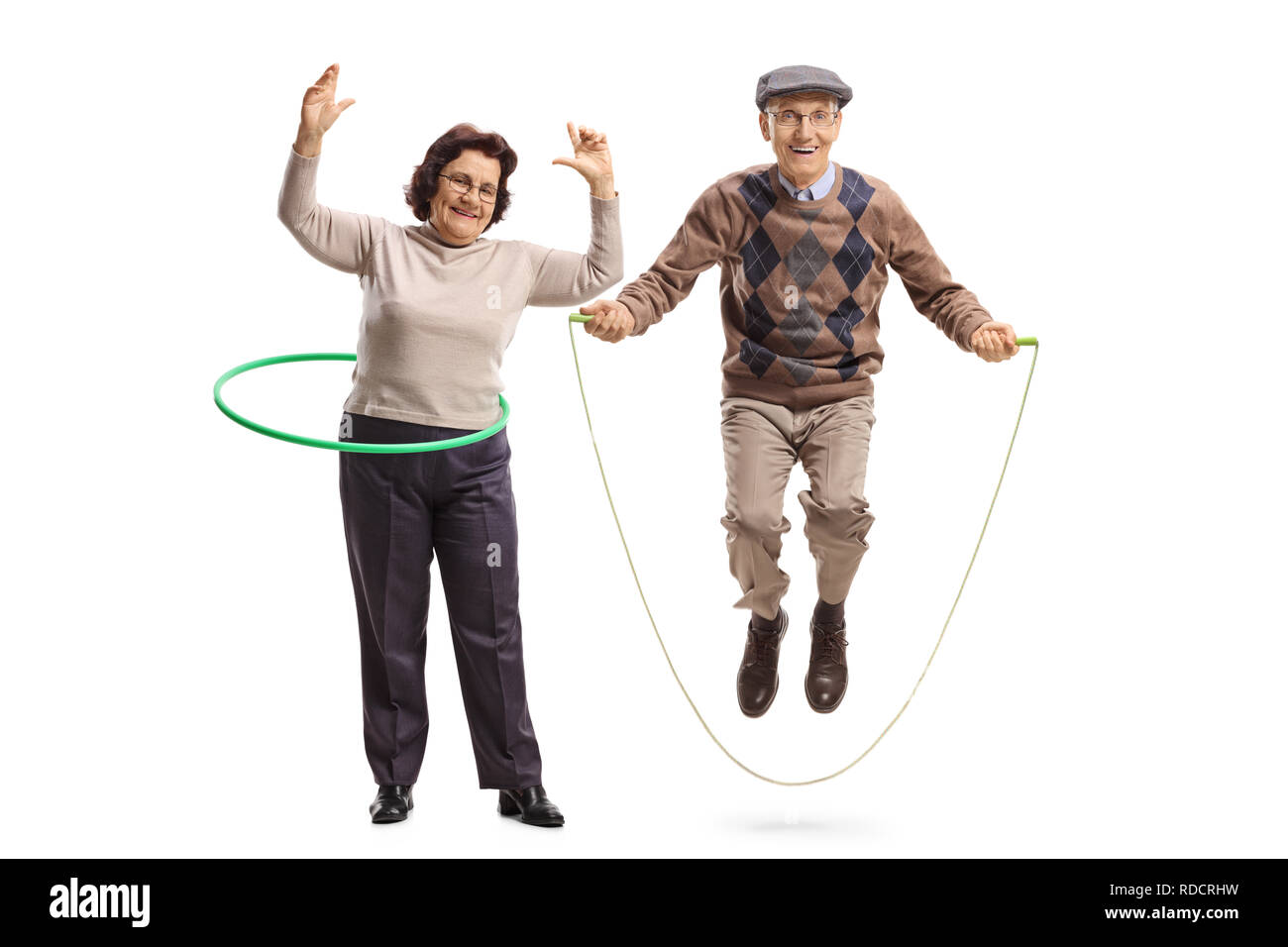 Full length portrait of an elderly woman with a hula hoop and a senior man jumping with a skipping rope isolated on white background Stock Photo