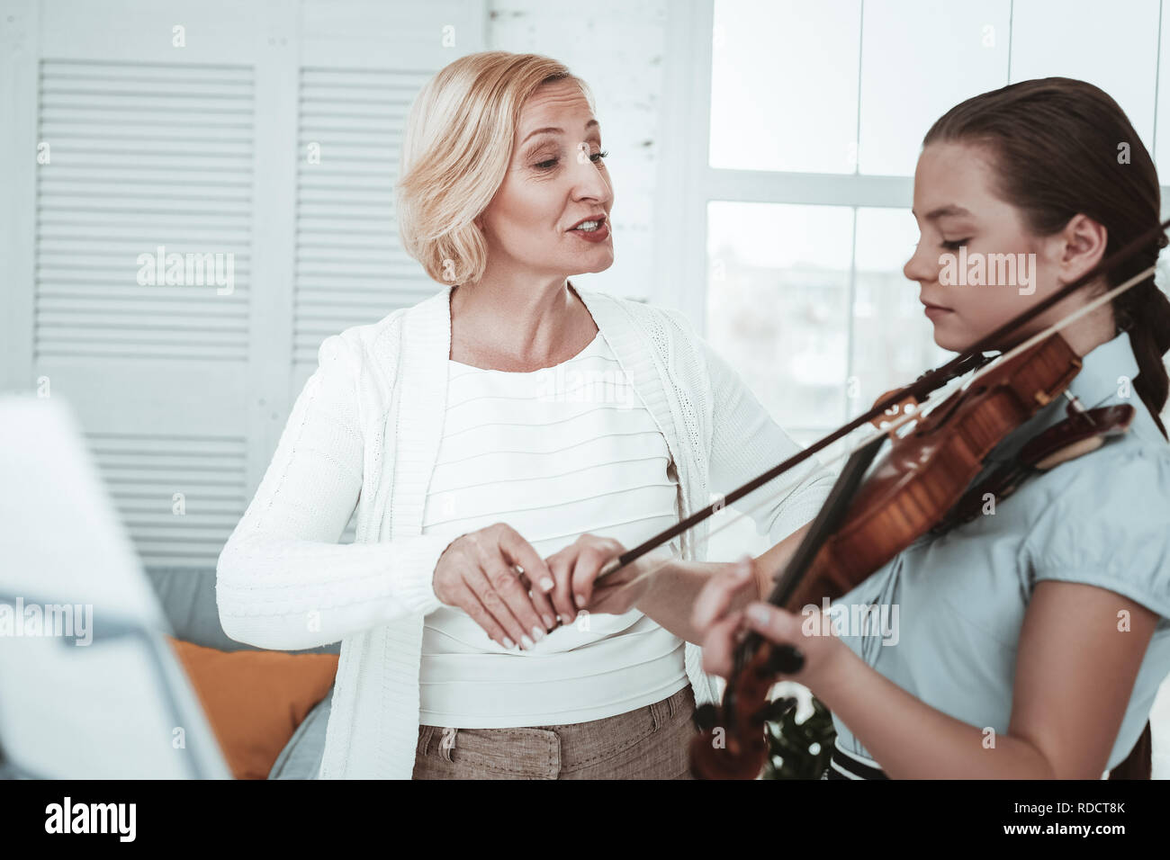 Professional female teacher teaching how to play the violin stock photo