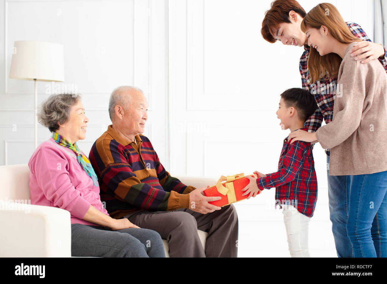 grandchild with parents giving a gift to grandparents Stock Photo Alamy